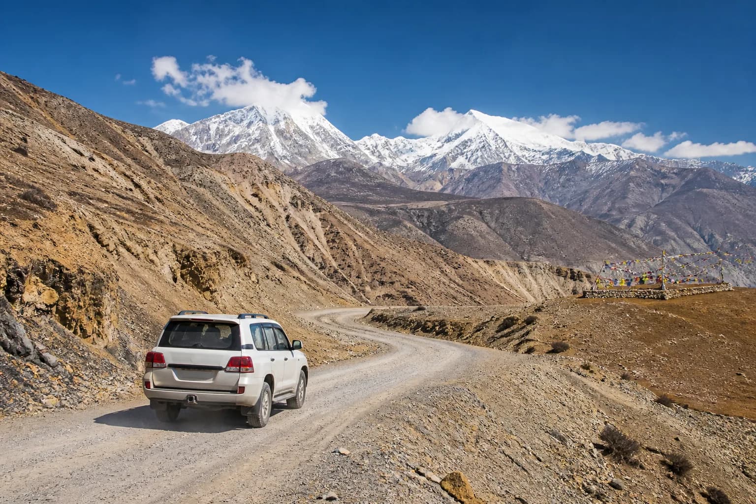 A white SUV traveling on a high-altitude mountain road